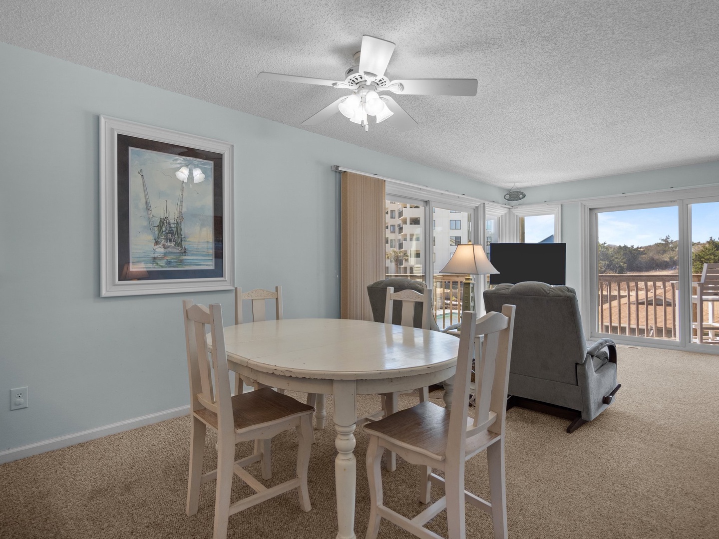 Relax in your bright dining and living space with coastal artwork and comfortable seating while enjoying natural light from large windows.