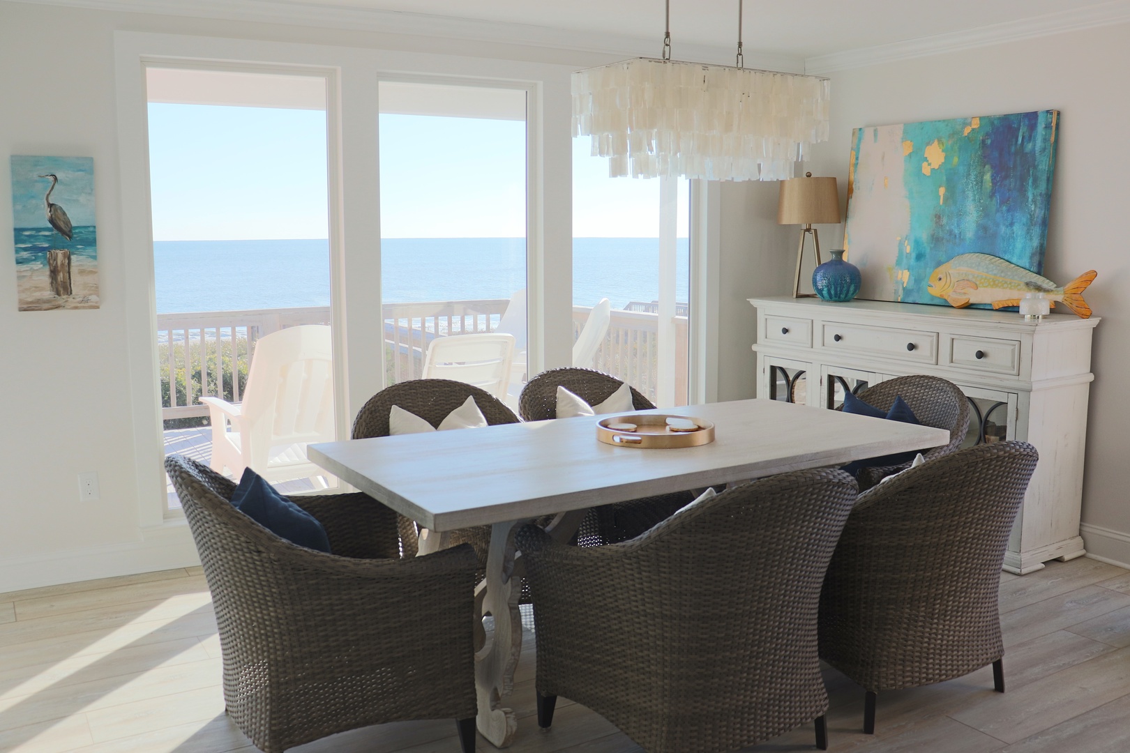 Gather around your oceanfront dining table where coastal artwork and sea views create the perfect backdrop for memorable meals together.