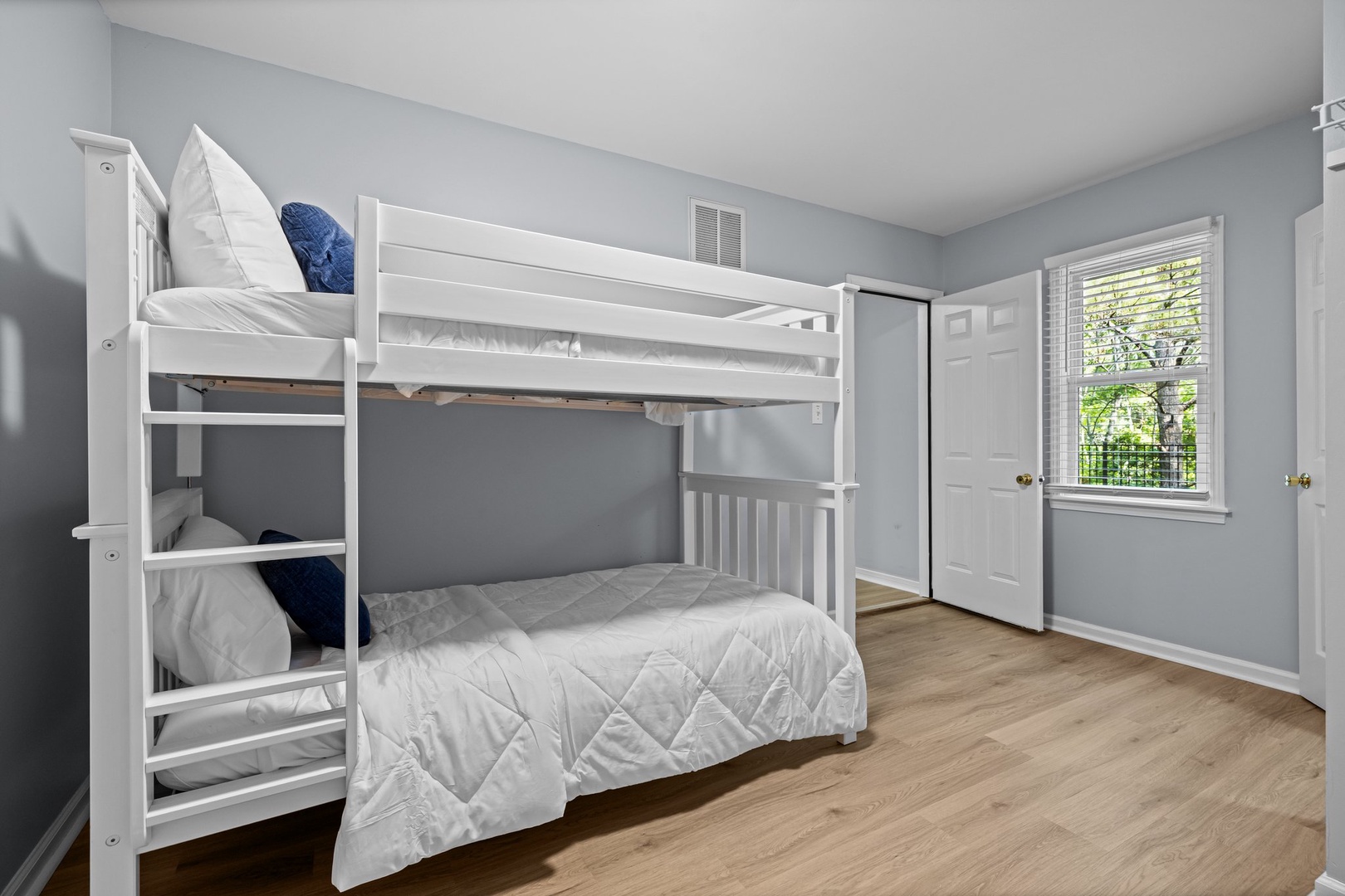 Your kids will love this bright bunk room with cozy white bedding and a window view of leafy trees.