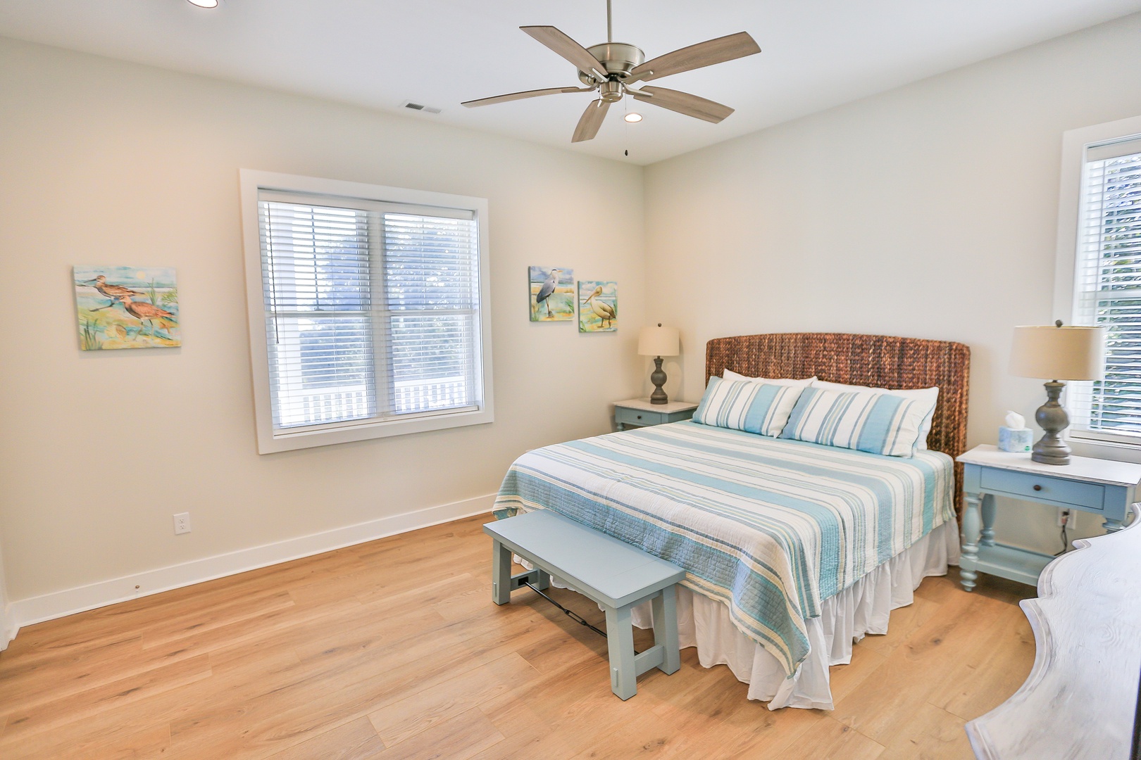 Unwind in your peaceful bedroom featuring a wicker headboard, soft coastal linens, and gentle ceiling fan to keep you comfortable.