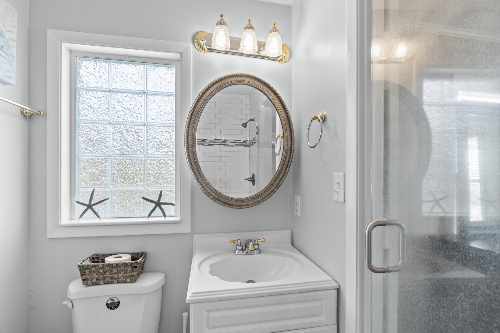 Refresh in your elegant coastal-themed bathroom featuring nautical touches, bright natural light, and a spacious glass shower for your comfort.