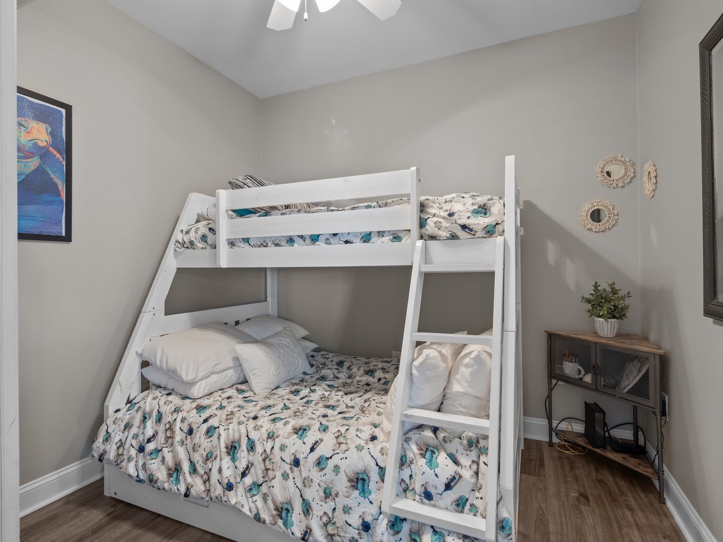 Your kids will love this cozy bunk bed setup with colorful bedding, ceiling fan, and fun decor to make bedtime an adventure.