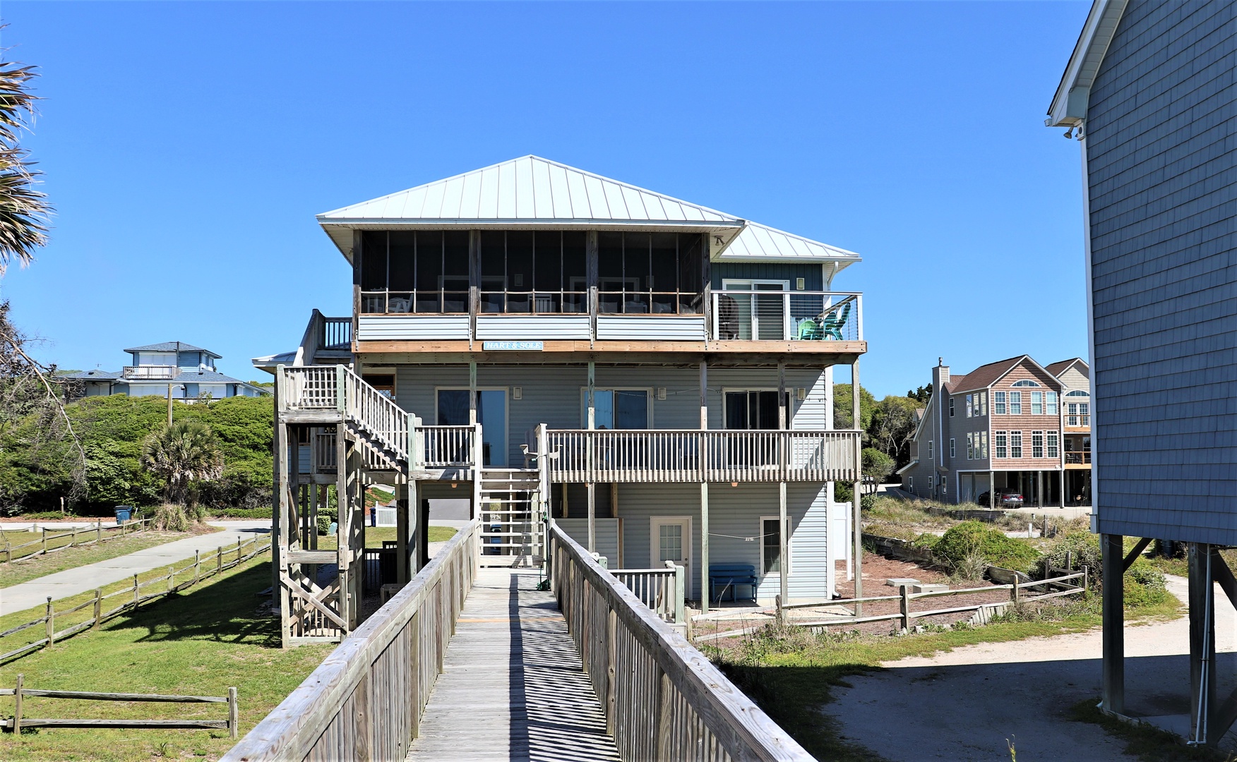 Coastal vacation home with multiple decks and elevated design, situated in a peaceful beach community with nearby properties.