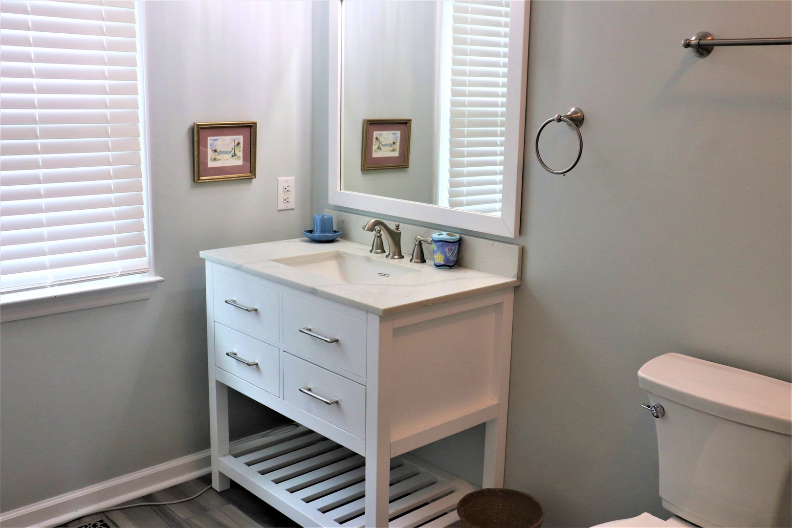 Your bright, serene bathroom features a elegant vanity with ample storage and natural light from windows with privacy blinds.