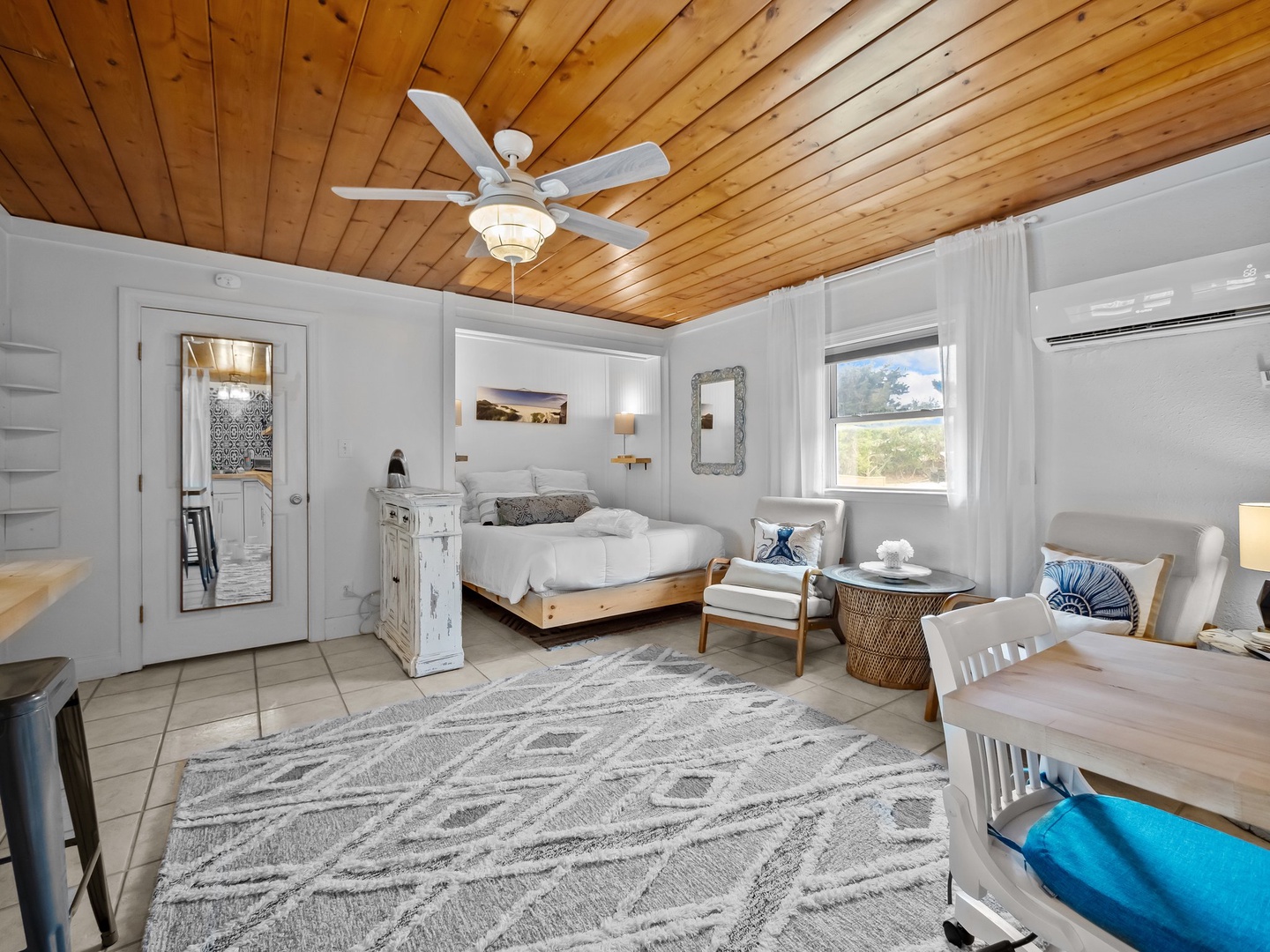 Relax beneath stunning wood beam ceilings in your coastal-inspired bedroom, featuring modern comfort with whitewashed furniture and nautical touches.