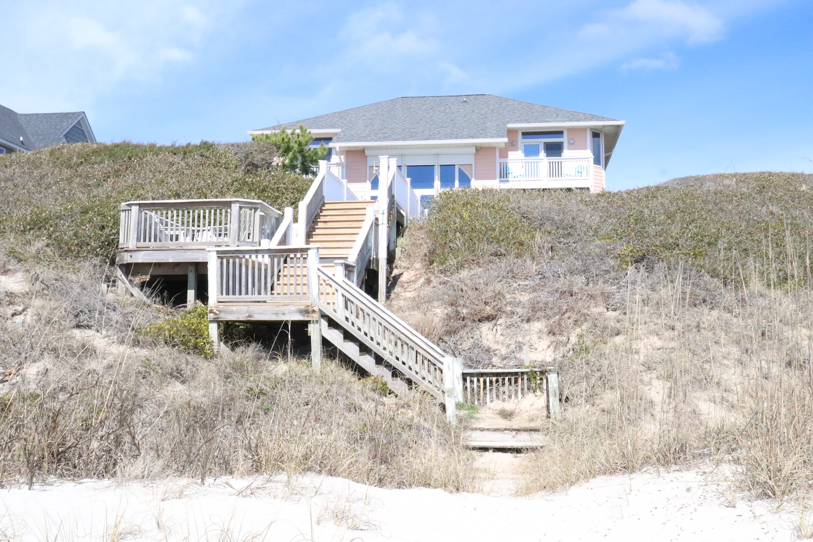 Charming beachfront home perched on natural dunes with private walkway leading directly to pristine sandy shores.