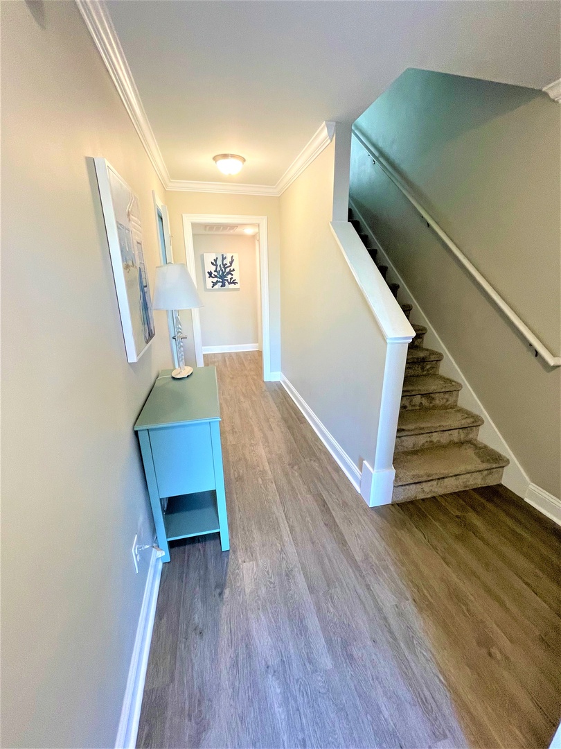 Step into your bright, welcoming hallway with coastal-inspired decor and polished floors that lead you upstairs to comfort.