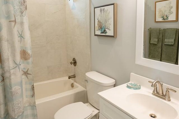 Your private bathroom offers a relaxing tub shower combo with coastal charm and all the essentials for a refreshing stay.