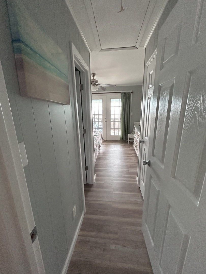 Walk through this bright hallway with gleaming hardwood floors connecting your private spaces to the sun-filled living area ahead.