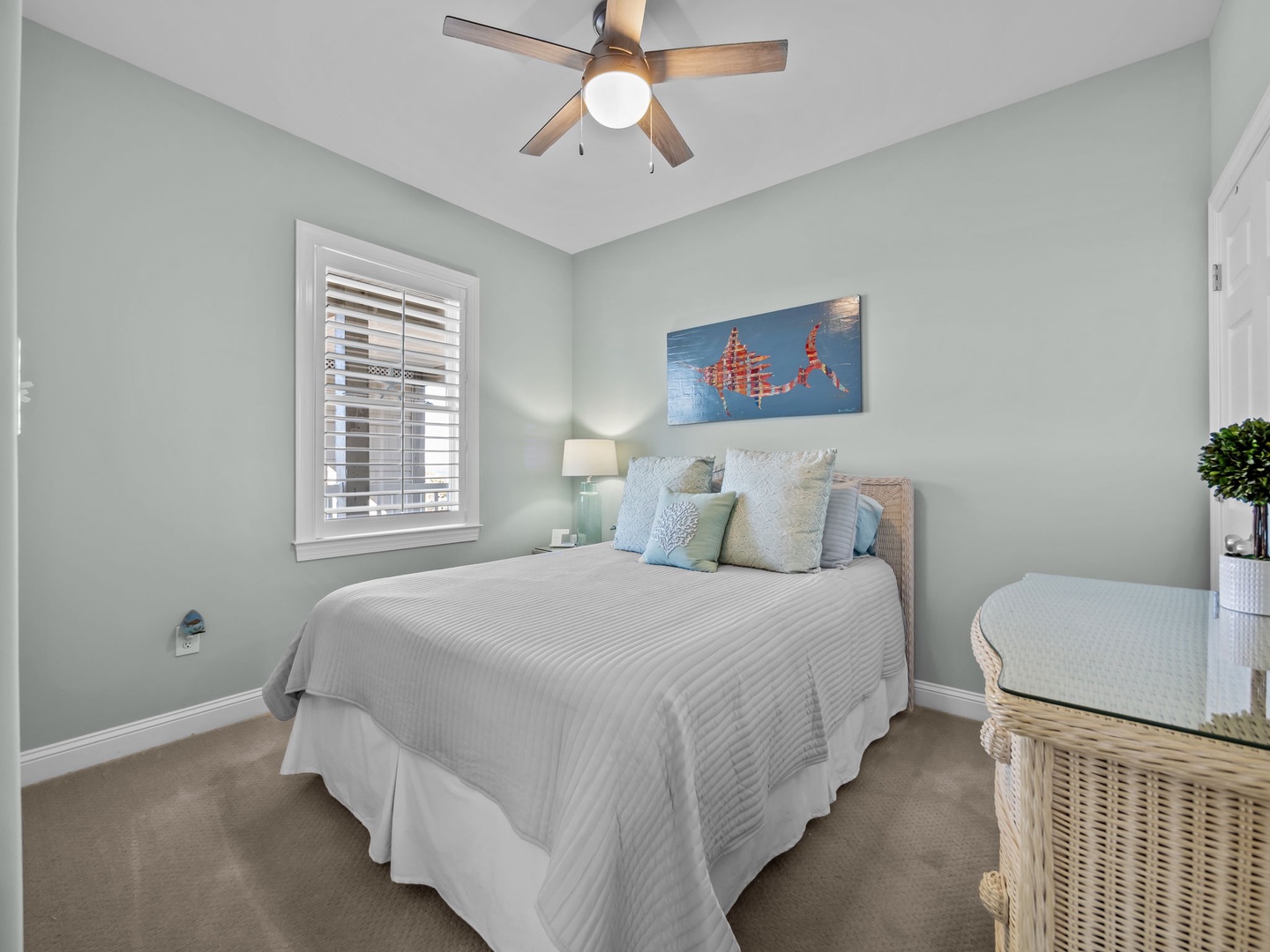 Your peaceful bedroom sanctuary features crisp linens, coastal artwork, and gentle ceiling fan breeze for restful nights.