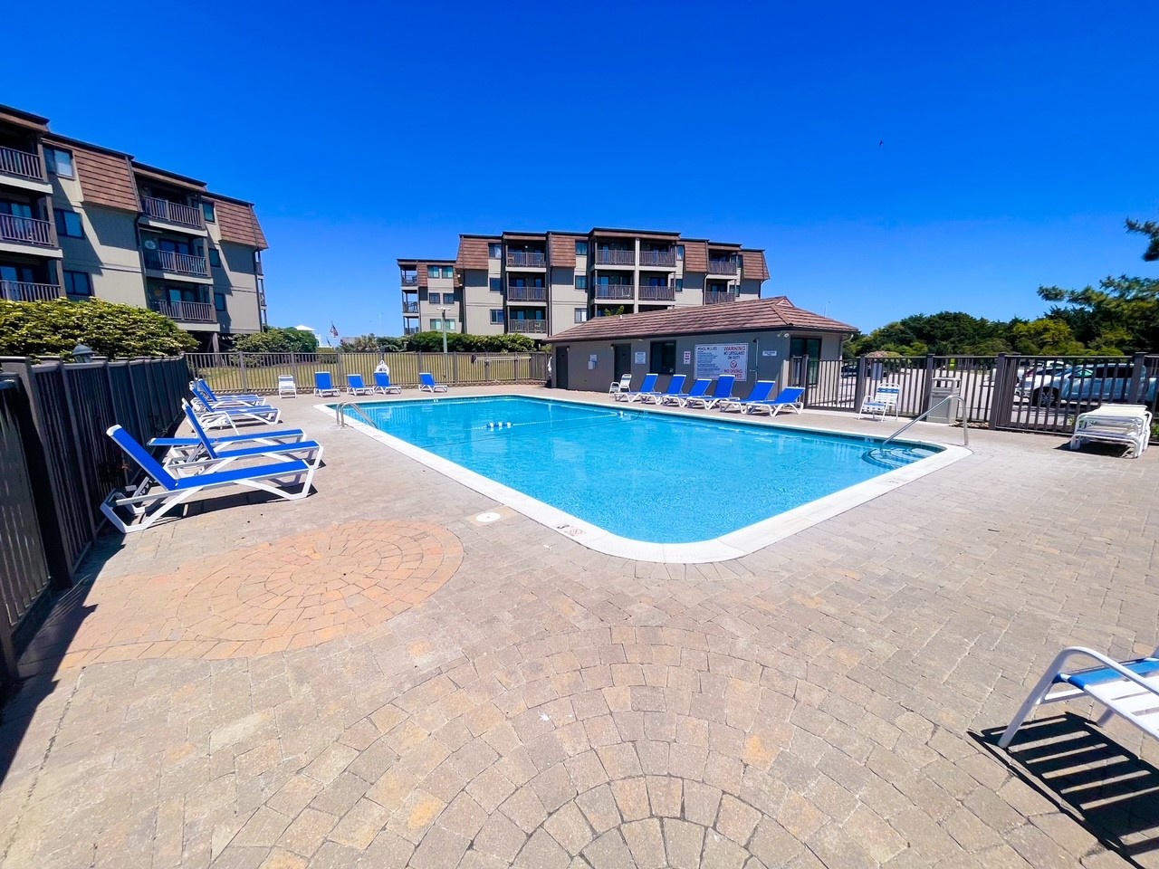 Dive into crystal-clear waters surrounded by comfortable loungers on elegant brick pavers, creating your perfect poolside retreat.