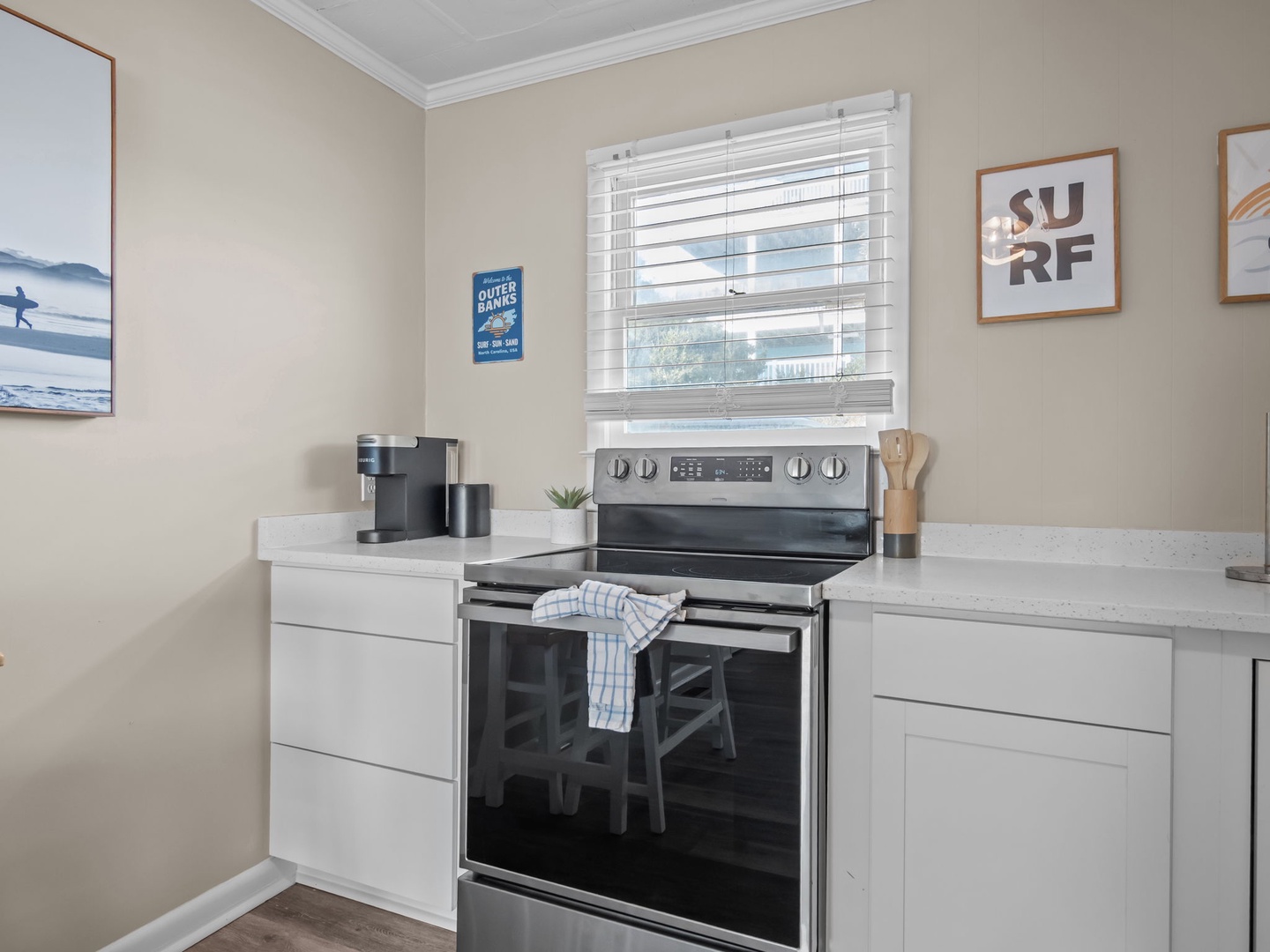 Your bright kitchen awaits with sleek white cabinetry, modern stainless appliances, and cheerful coastal artwork to inspire your culinary adventures.