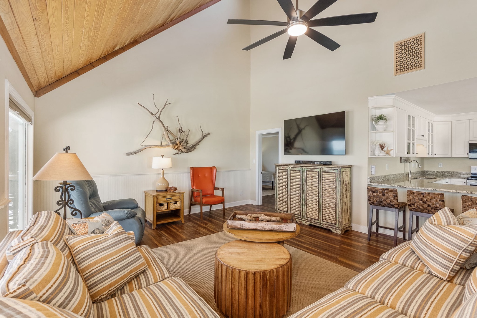 Relax in your stunning open-concept living space with soaring wood beam ceilings and thoughtfully curated coastal decor.