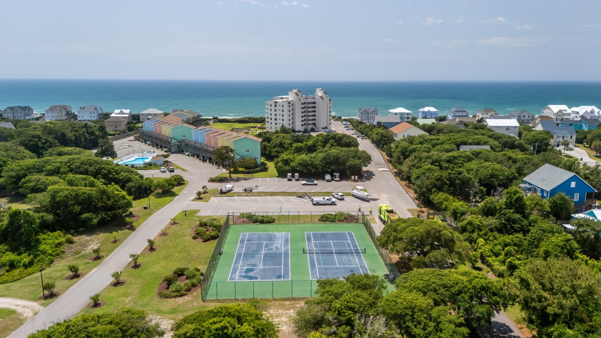 Coastal resort community featuring tennis courts, swimming pool, and beachfront access with lush landscaping throughout the property.