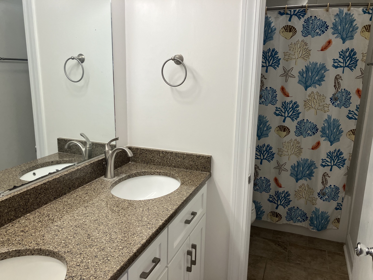 Your private bathroom features dual sinks with granite countertops and a charming coastal-themed shower with coral and starfish patterns.