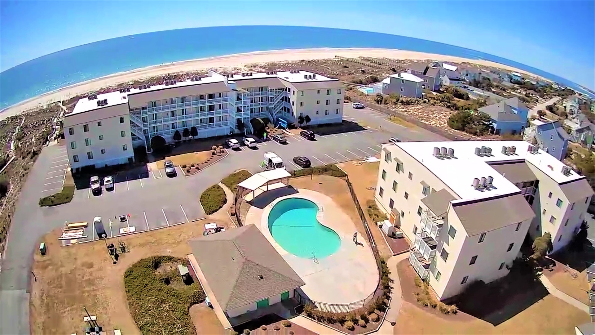 Beachfront resort complex with swimming pool just steps from pristine sandy shores and crystal blue ocean waters.