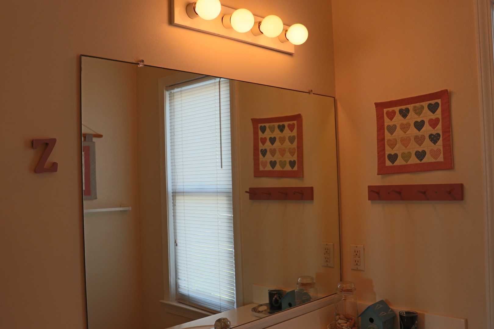 Freshen up in your private bathroom with warm vanity lighting and charming heart-themed artwork that makes every morning feel special.