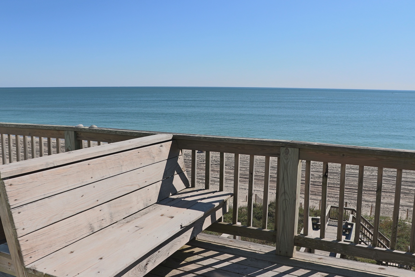 Expansive ocean views stretch to the horizon from this elevated wooden deck overlooking pristine sandy beaches.