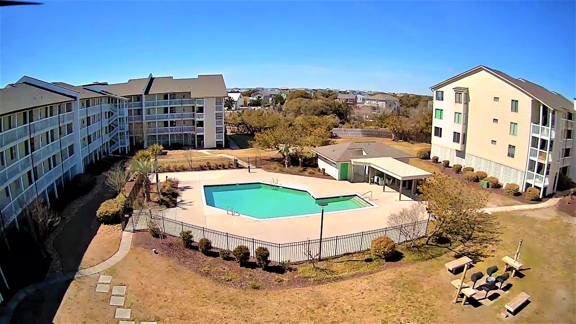 Aerial view of the property complex featuring multi-story buildings surrounding a central pool area with recreational facilities.