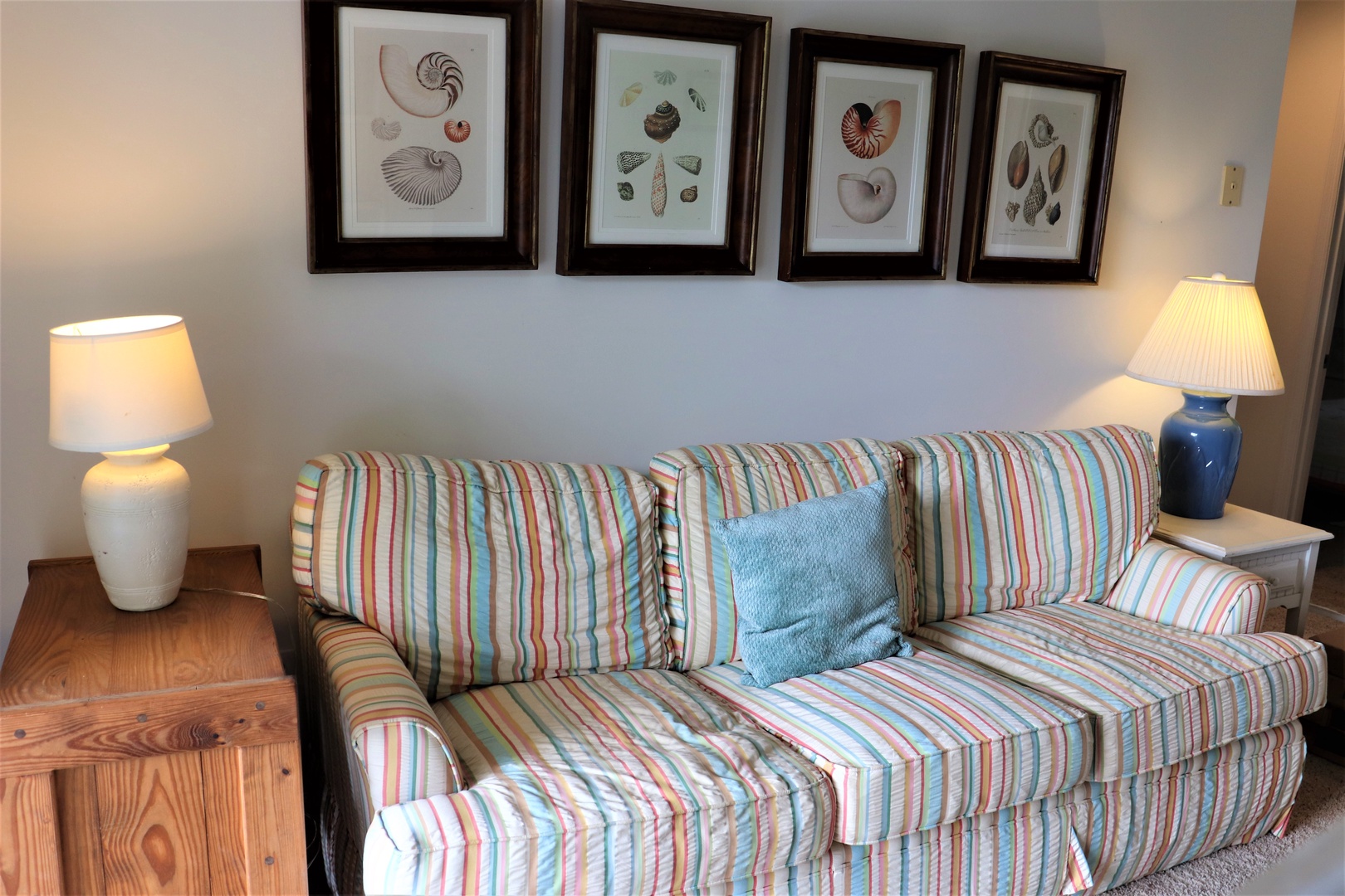 Sink into your comfortable striped sofa surrounded by coastal artwork and warm lamplight for the perfect evening unwind.