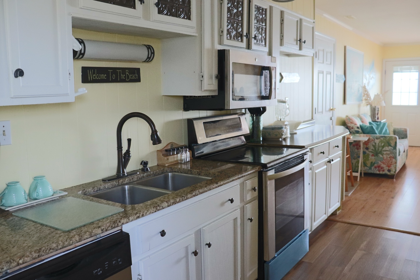 Your fully equipped kitchen awaits with granite counters, stainless appliances, and warm wood floors leading to your cozy living space.