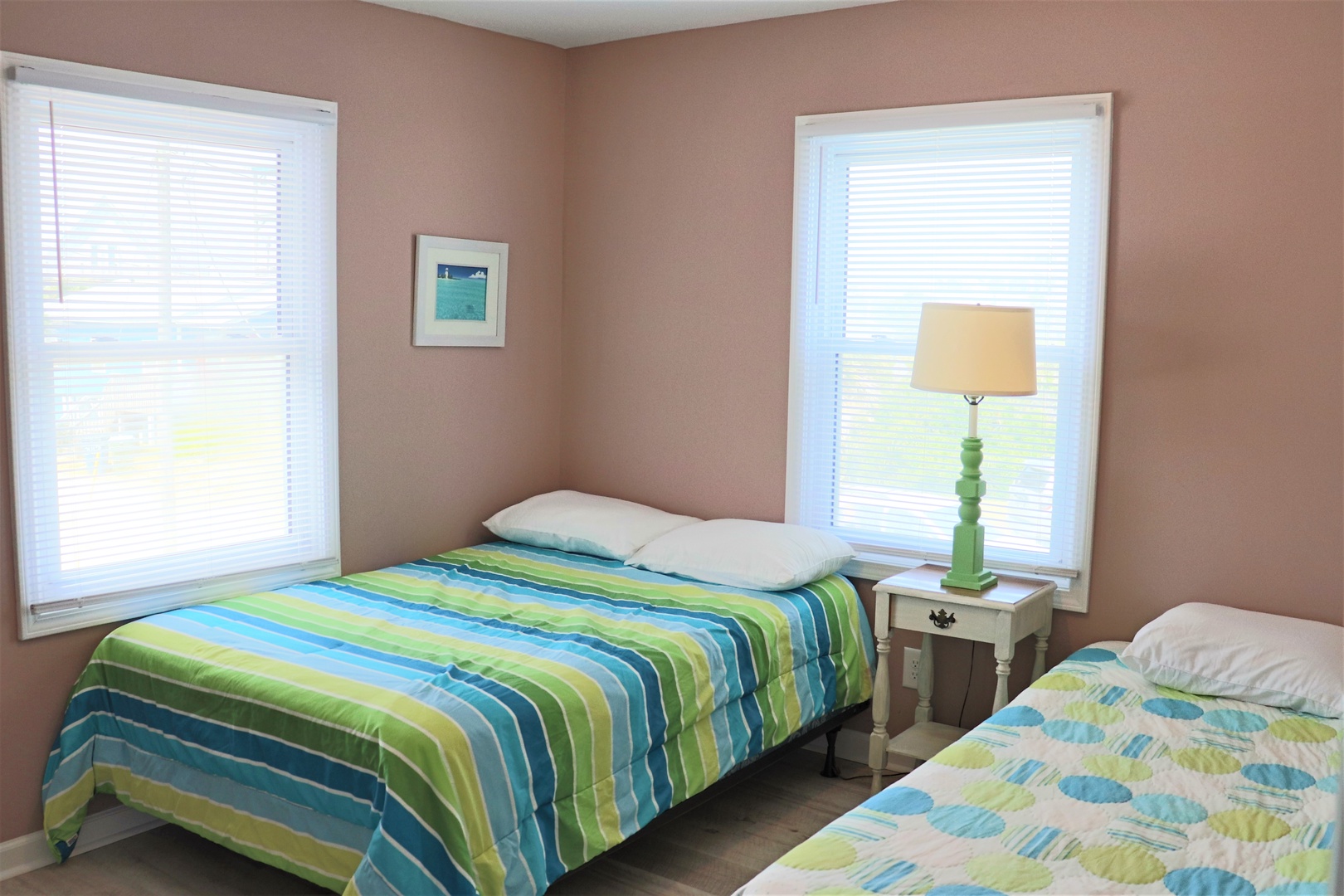 Drift off peacefully in your bright, cozy bedroom with twin beds adorned in cheerful green and blue linens.