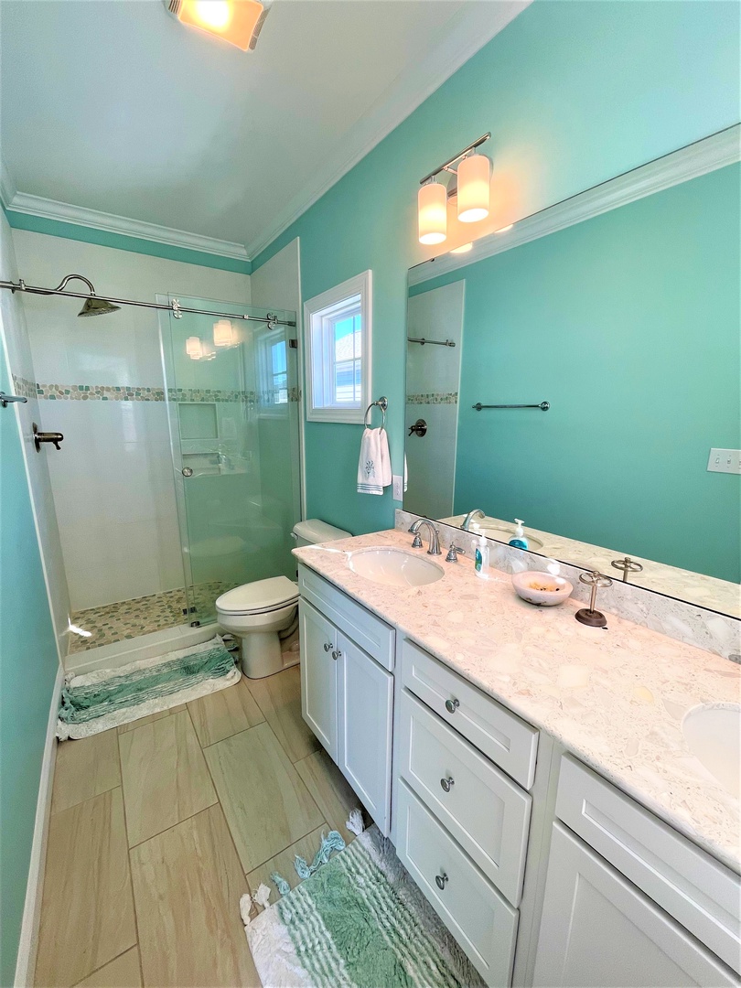 Refresh in your beautifully appointed bathroom featuring soothing mint walls, marble countertops, and a spacious glass-enclosed shower.