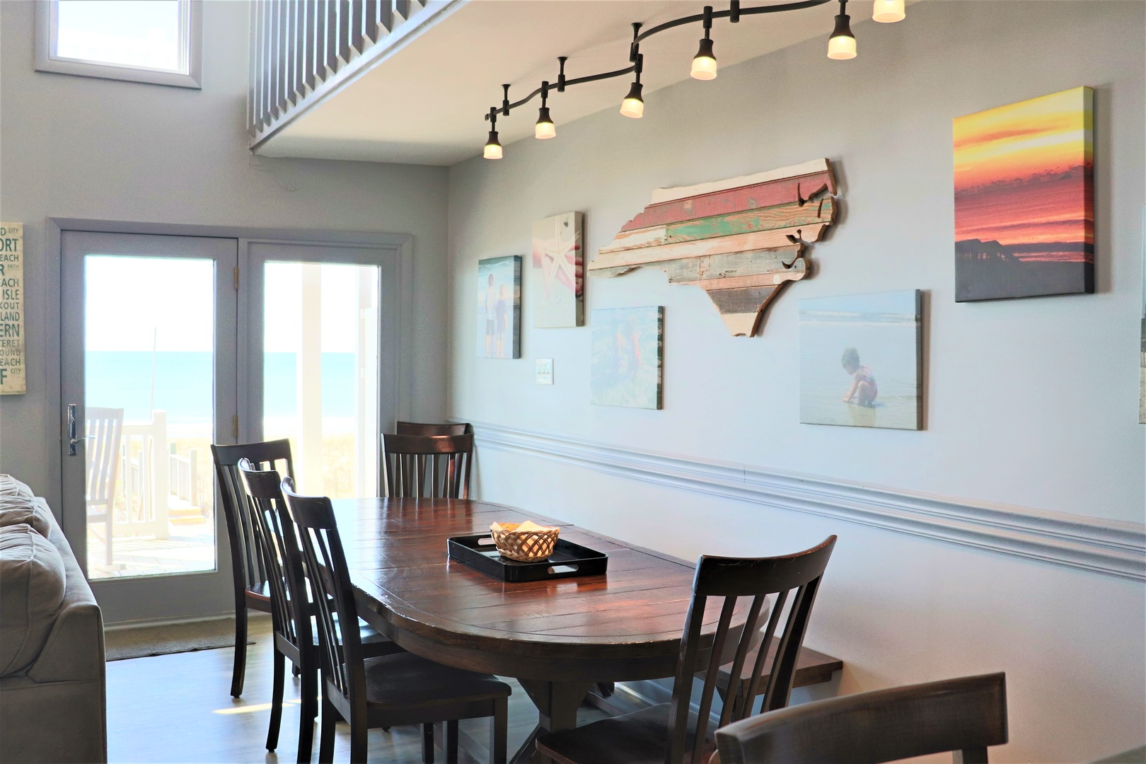 Gather around your stylish dining table while natural light streams through sliding glass doors. Beach-inspired art creates a coastal atmosphere perfect for memorable meals.