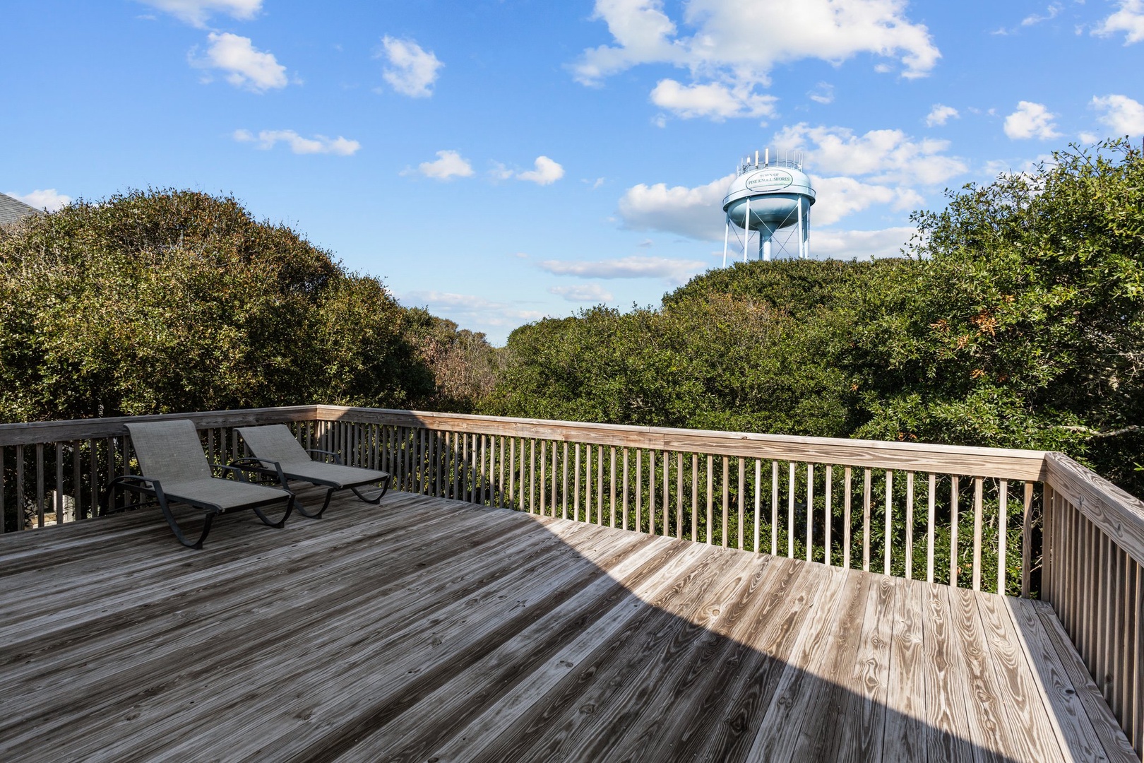 Spacious wooden deck overlooking lush trees and water tower, perfect for morning coffee or evening relaxation in the peaceful surroundings.