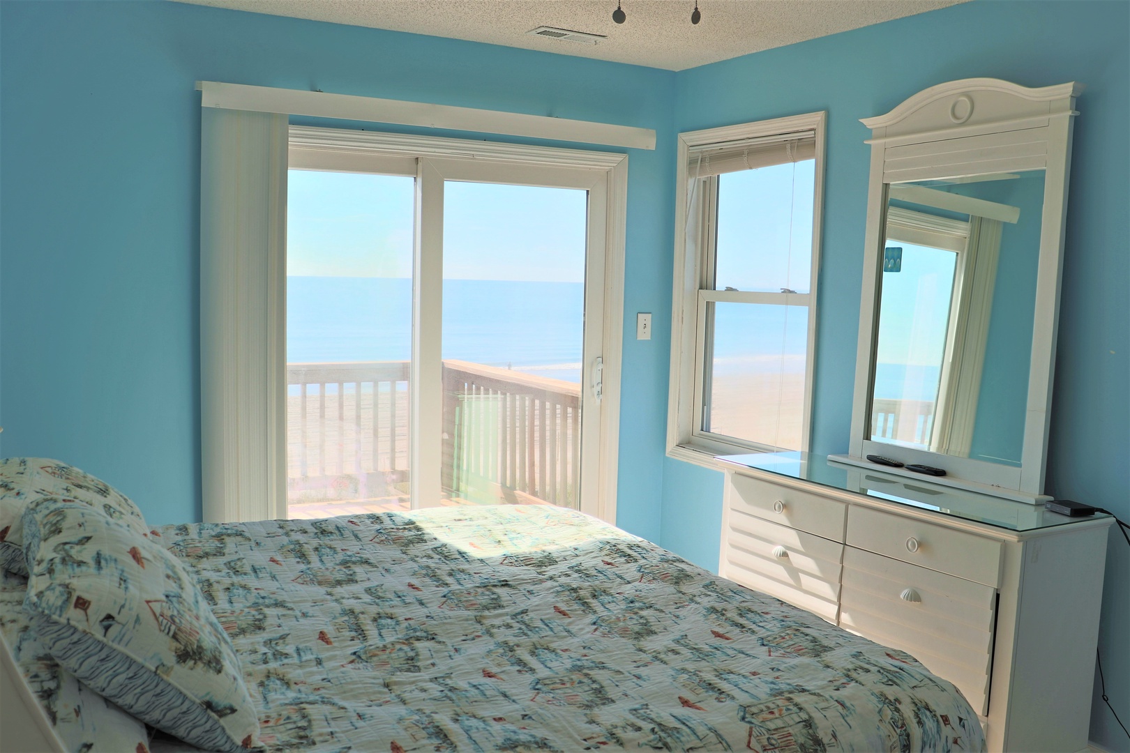 Wake up to breathtaking ocean views from your cozy coastal bedroom, where turquoise walls mirror the sea beyond your private balcony.