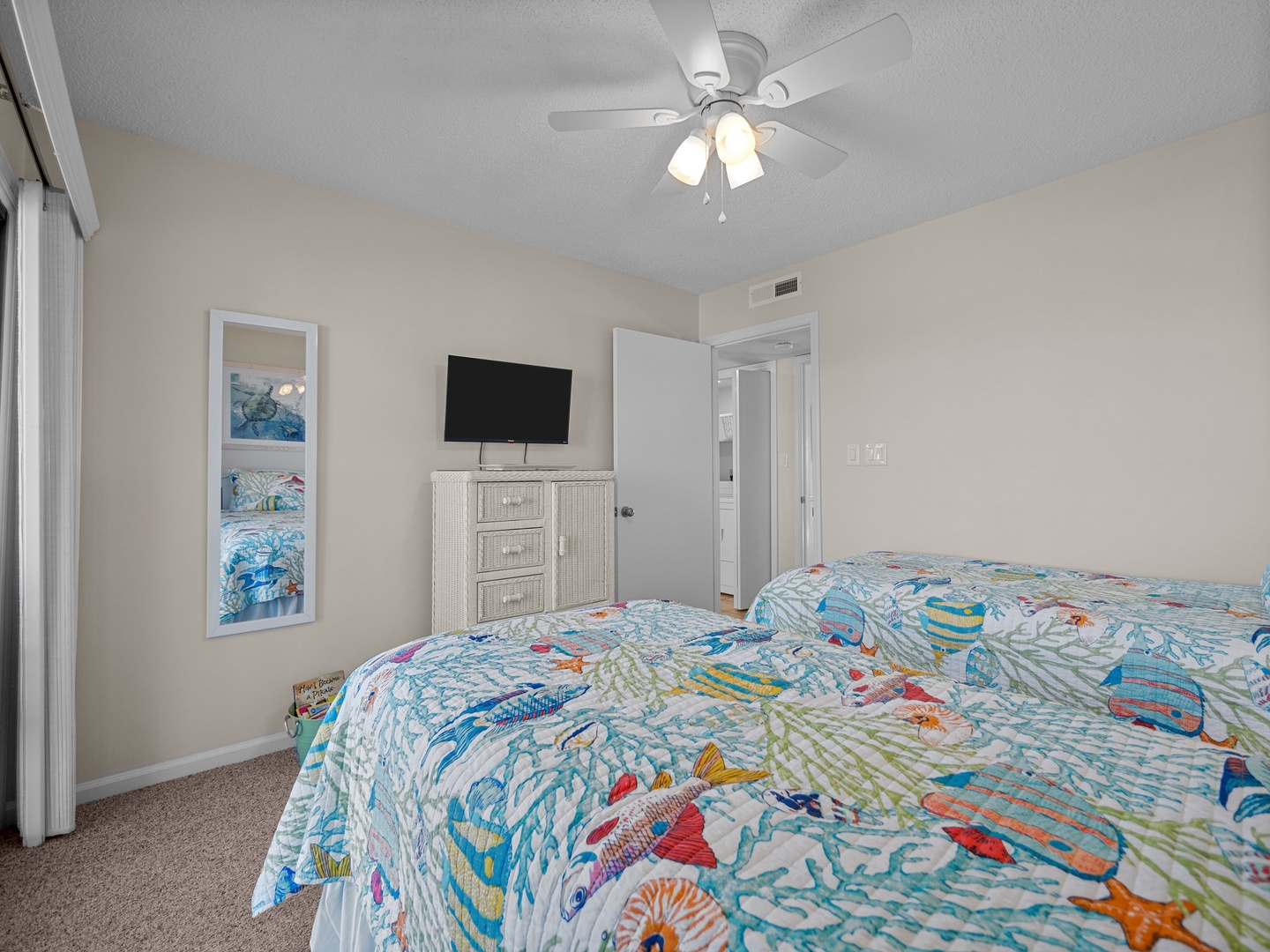 Rest comfortably in your bright bedroom with twin beds, ceiling fan, and cheerful ocean-themed bedding that sets a coastal vacation mood.