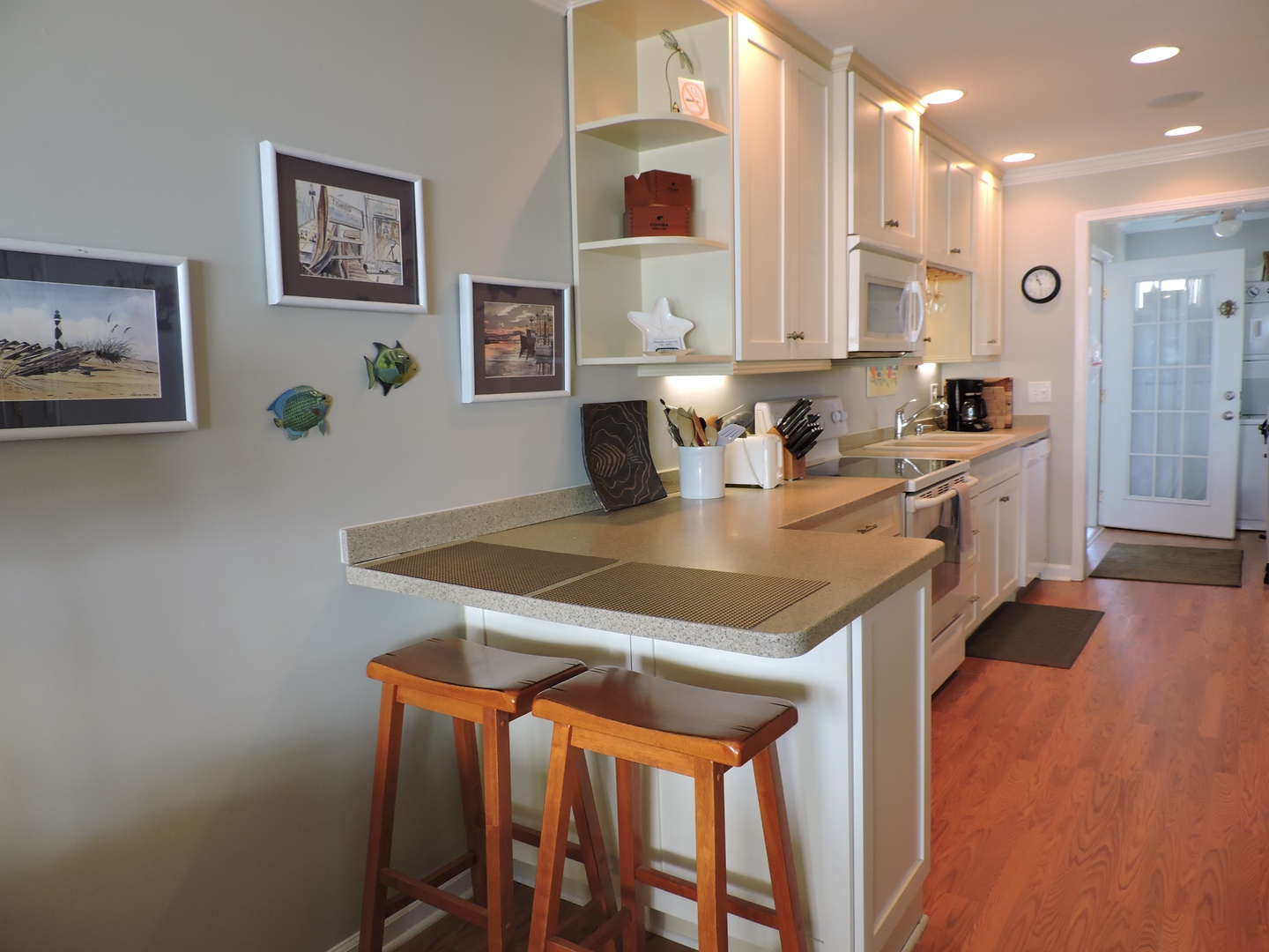 Your bright kitchen welcomes with white cabinets, warm countertops, and thoughtful details like coastal artwork that make cooking feel like home.
