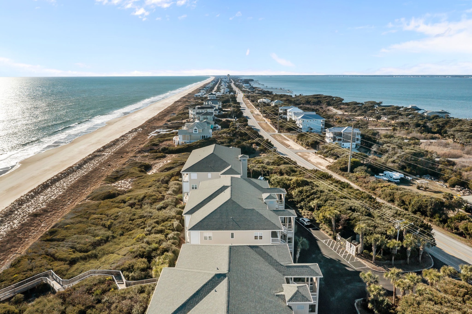 Stunning aerial view of beachfront vacation rental properties nestled between pristine coastline and natural dunes, offering the perfect coastal escape.