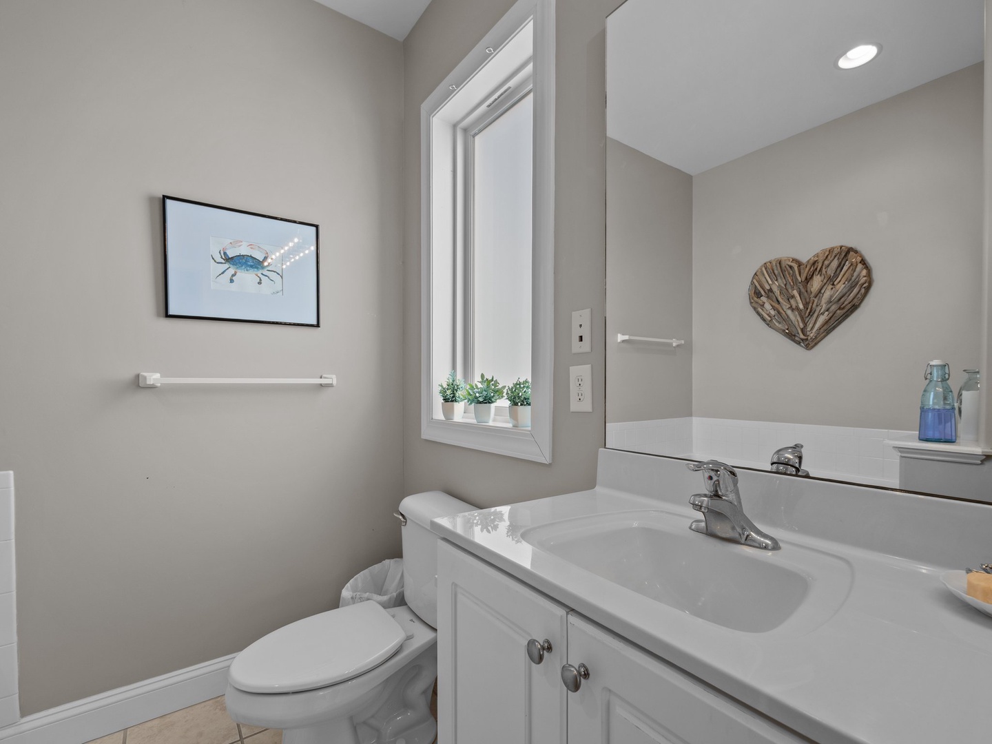 Your peaceful coastal bathroom features charming nautical artwork and driftwood accents, creating a serene retreat perfect for unwinding after beach days.