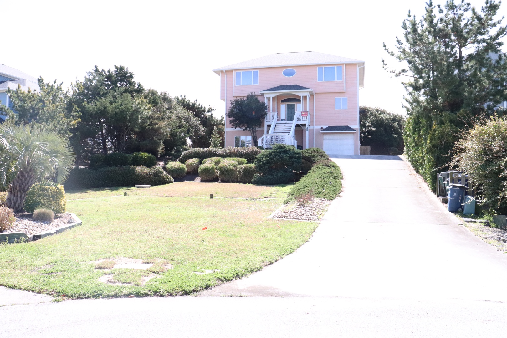 This charming pink beach house sits on beautifully landscaped grounds in a peaceful residential neighborhood.