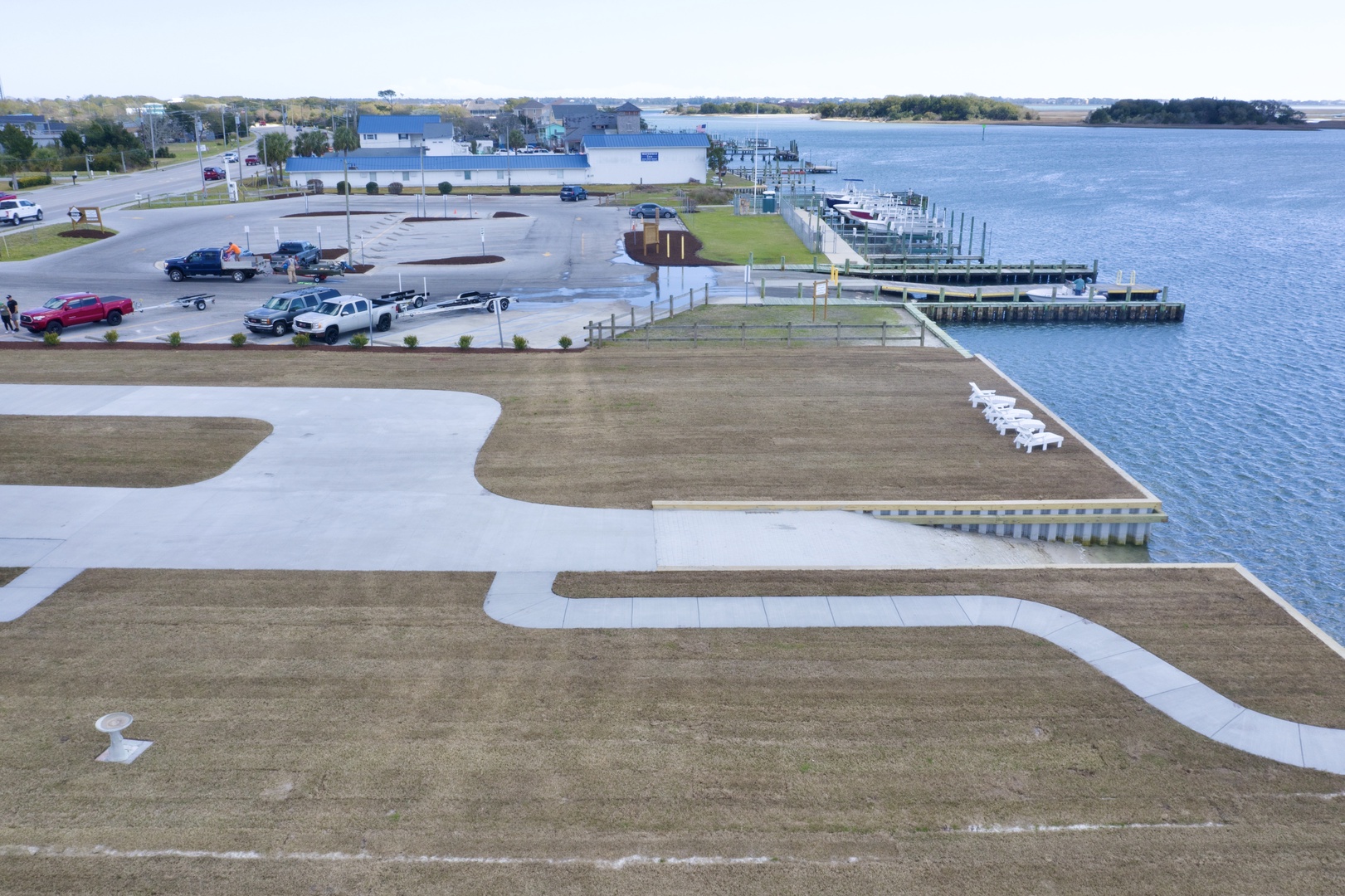 Aerial view of waterfront area with marina docks, parking facilities, and walking paths along the shoreline.