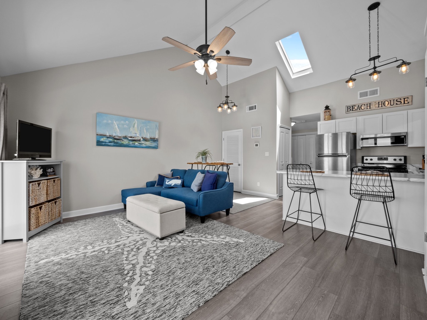 Unwind in your bright, open living space with soaring vaulted ceilings, coastal décor, and a comfortable blue sofa perfect for relaxing after beach days.