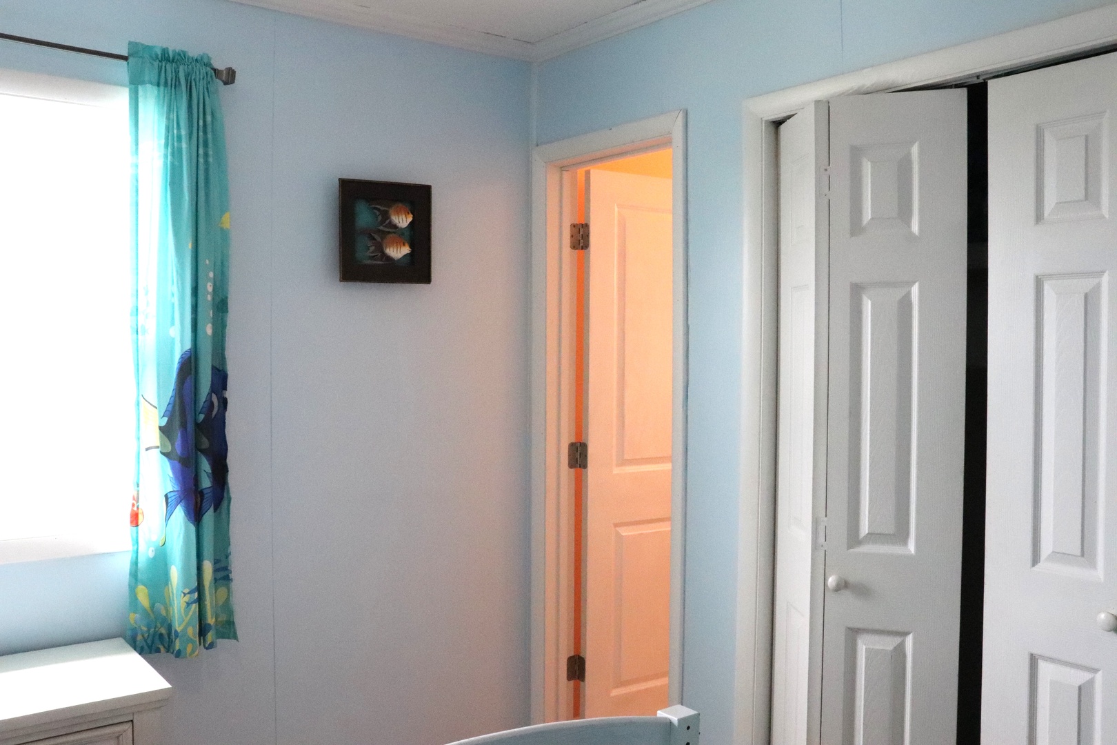 Light blue walls and playful ocean-themed curtains create a cheerful, beach-inspired space. Two doorways invite you to explore the rest of your vacation home.