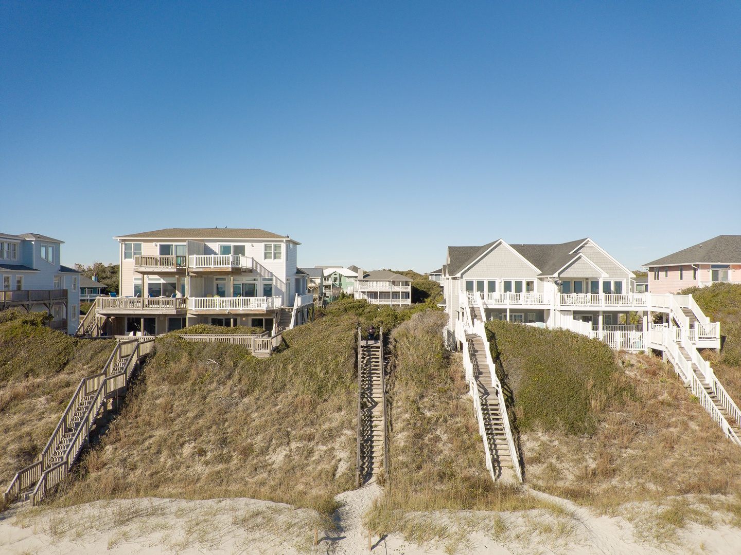 Coastal beachfront homes with elevated wooden walkways providing direct beach access in a charming seaside community.