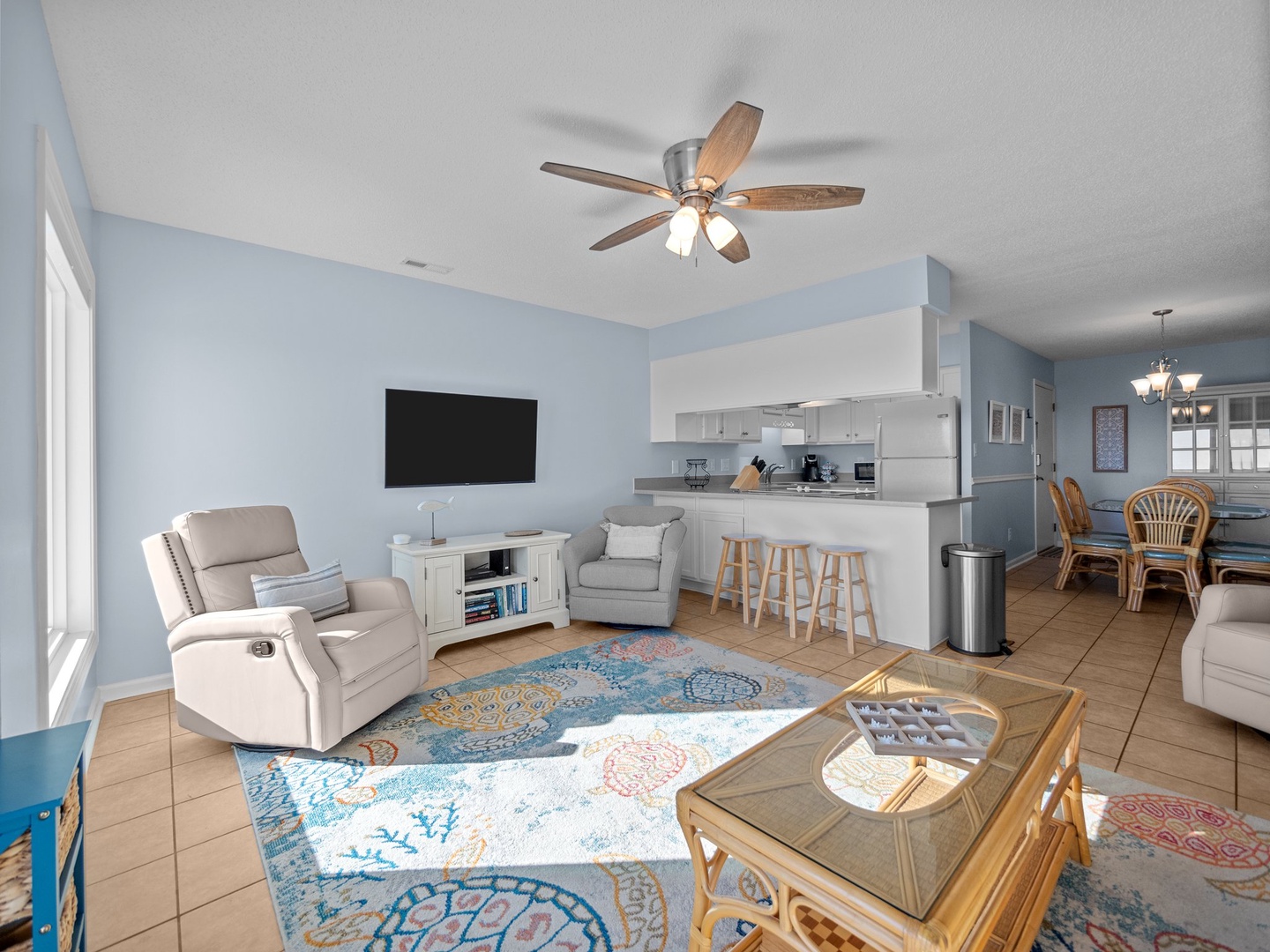 Unwind in your spacious living room where modern comfort meets coastal charm, featuring cozy recliners and an open kitchen perfect for your stay.