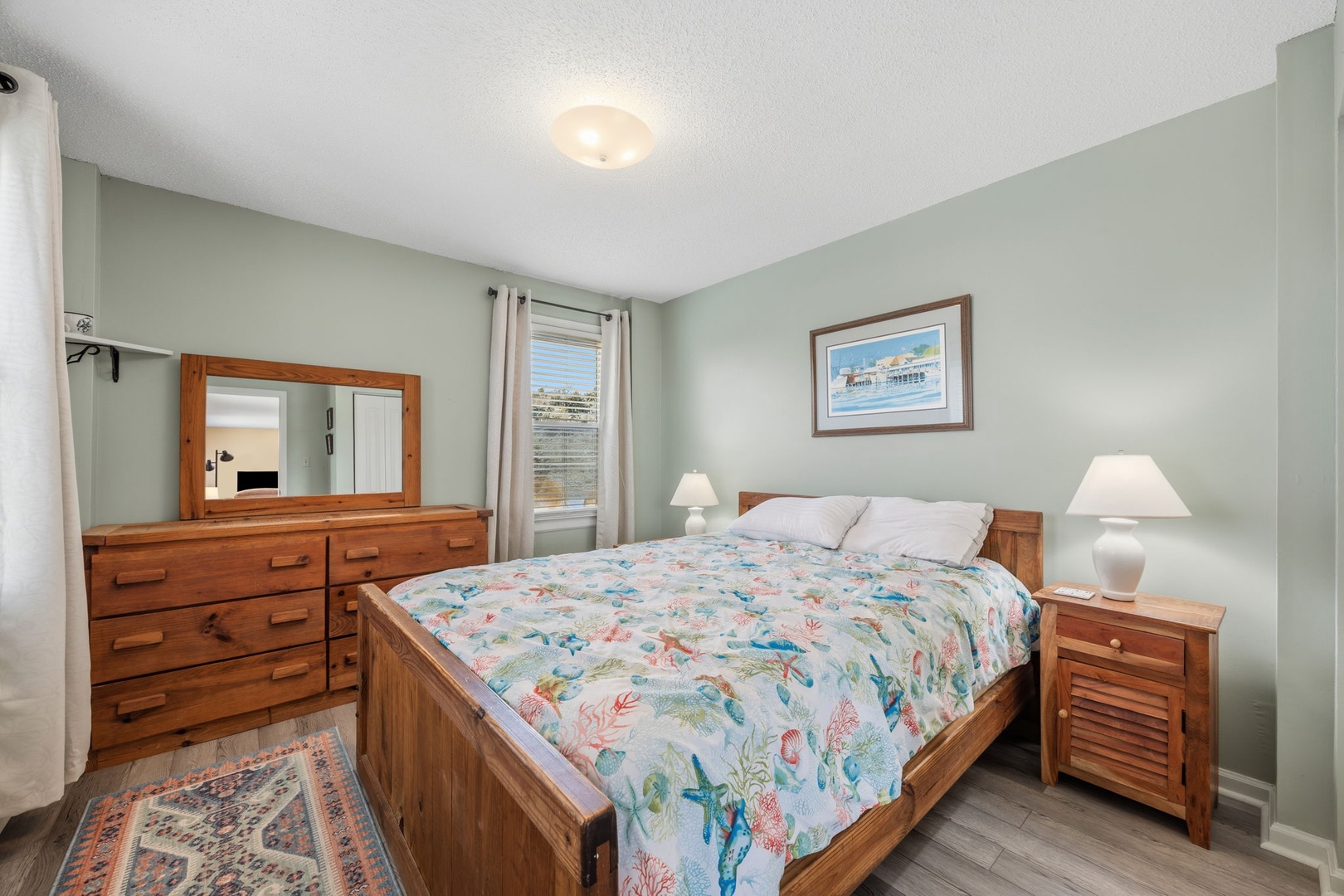 Drift off to sleep surrounded by warm wood furnishings and soft green walls that create a calming coastal retreat.