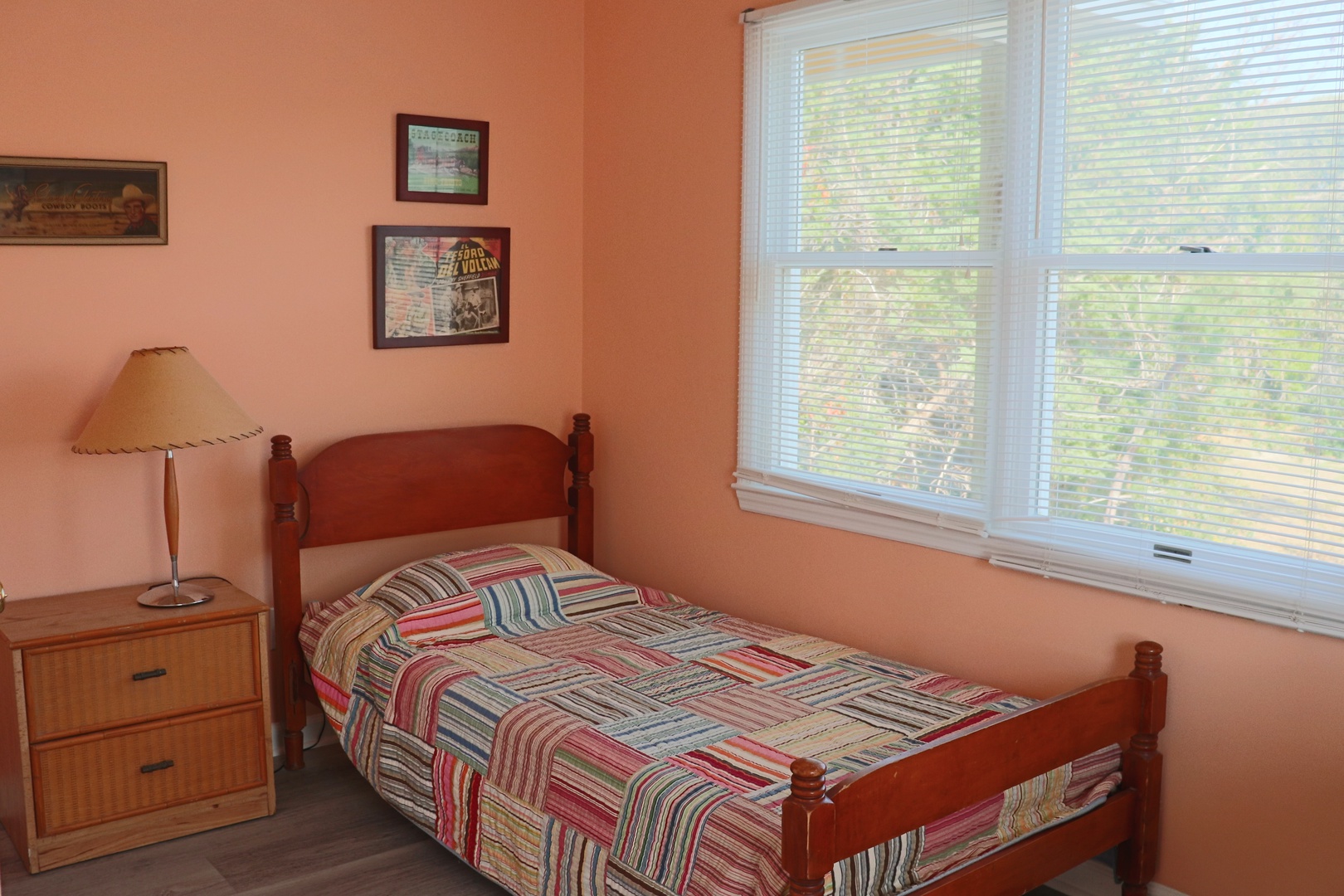 Unwind in your cozy bedroom featuring warm peachy walls and a colorful striped quilt, with natural light streaming through windows.