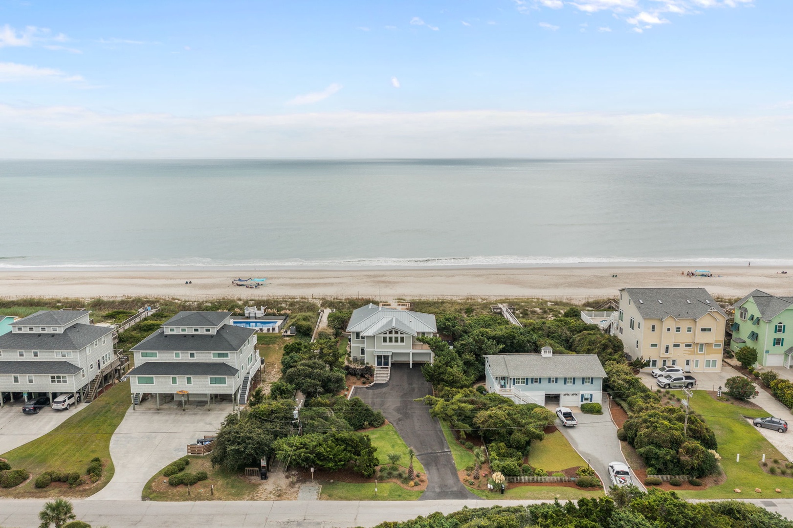Beachfront vacation homes nestled between lush coastal vegetation and pristine sandy shores, offering direct beach access.
