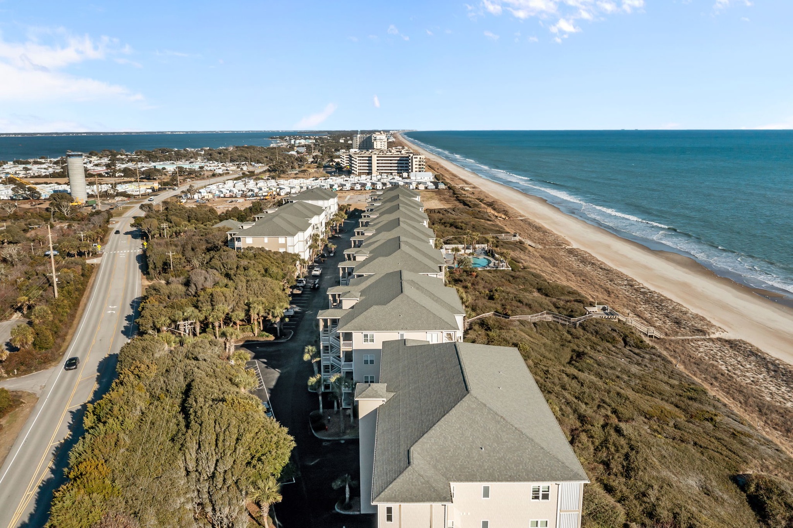 Coastal community with beachfront homes nestled between ocean waves and natural dunes, offering peaceful seaside living near local amenities.