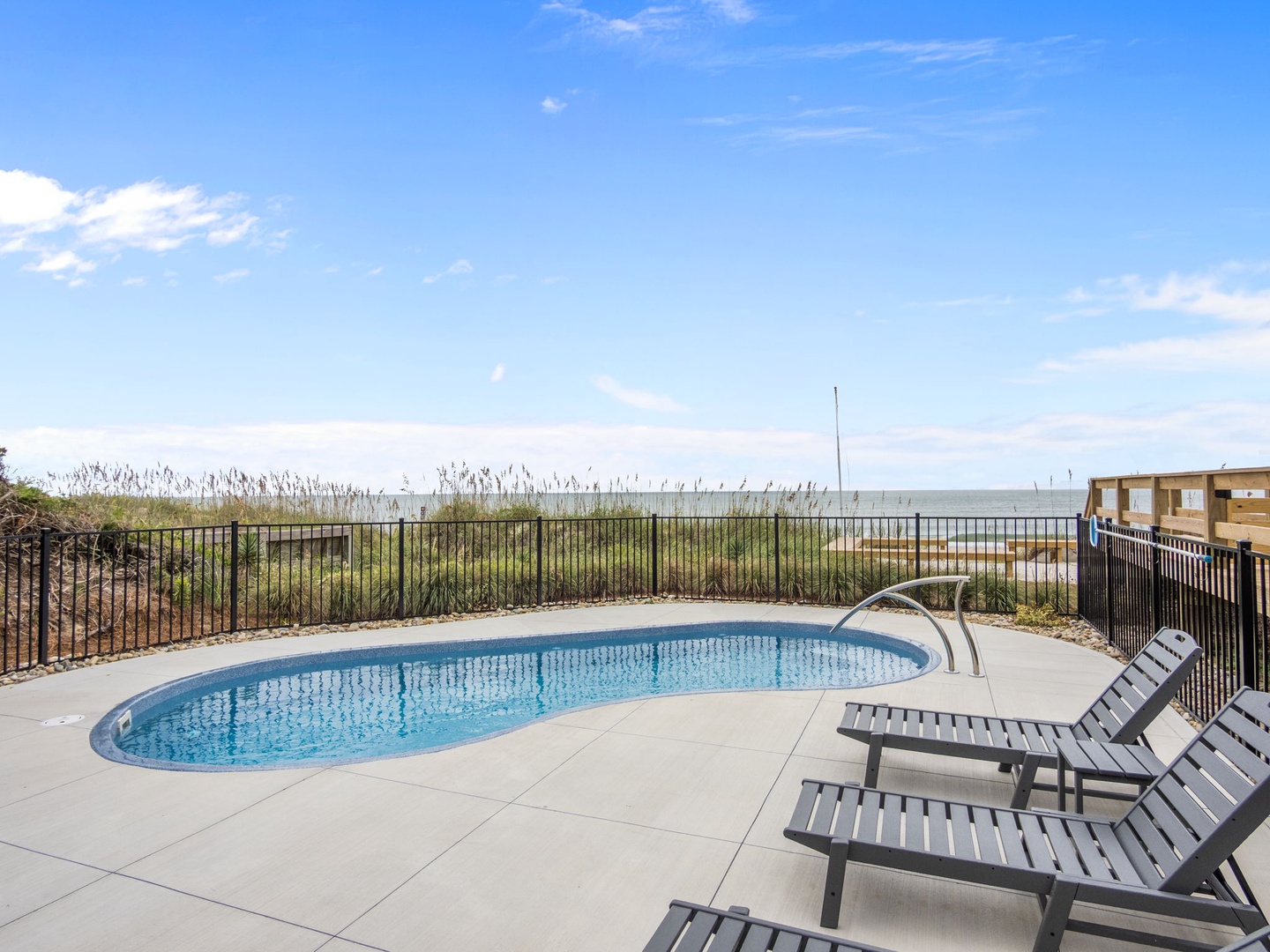 Soak up the sun by your private oval pool with stunning ocean views and comfortable lounge chairs for perfect relaxation.
