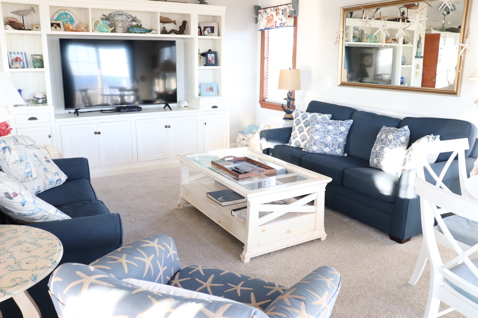 Sink into plush coastal seating where navy blues meet crisp whites, creating your perfect retreat for movie nights and morning coffee.
