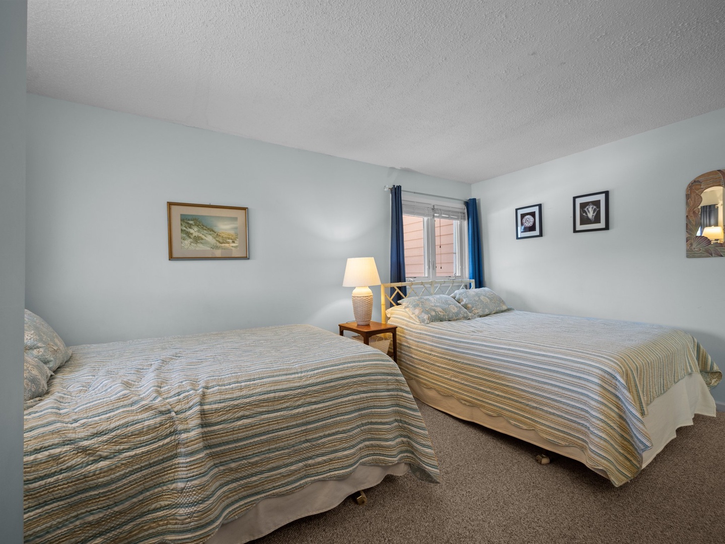 Rest peacefully in your coastal-inspired bedroom with two comfortable beds, soft linens, and gentle natural light streaming through the window.