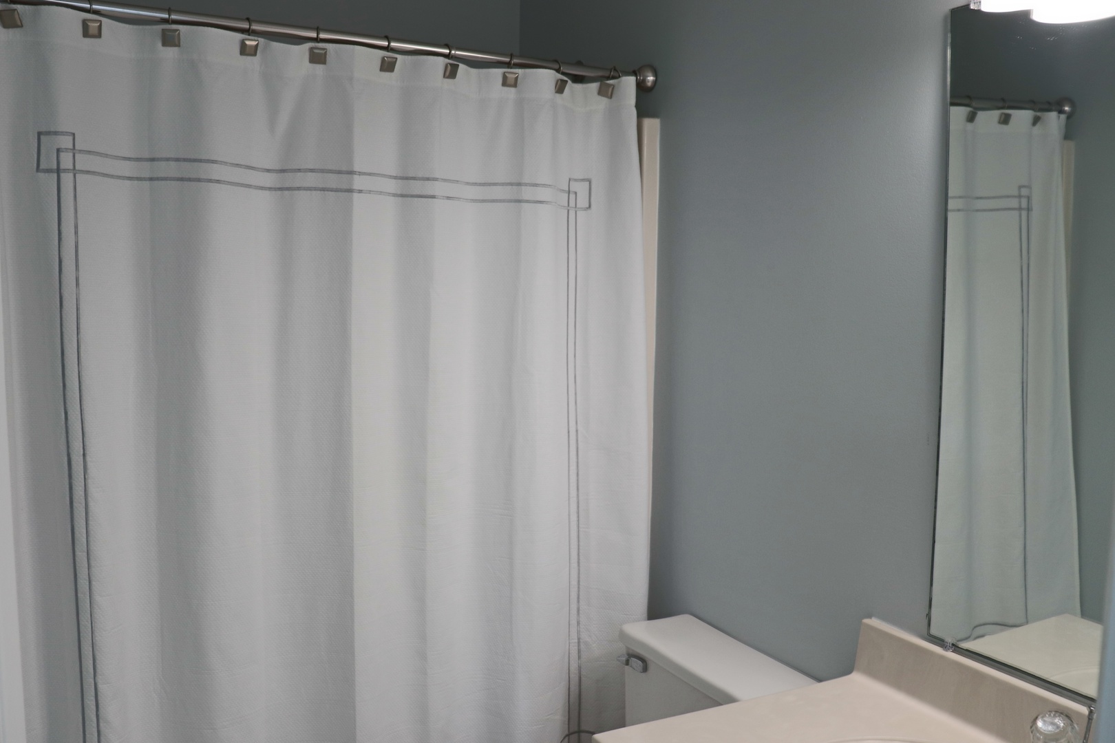 Step into your private bathroom featuring a clean shower with stylish curtain and convenient vanity mirror for your daily routines.