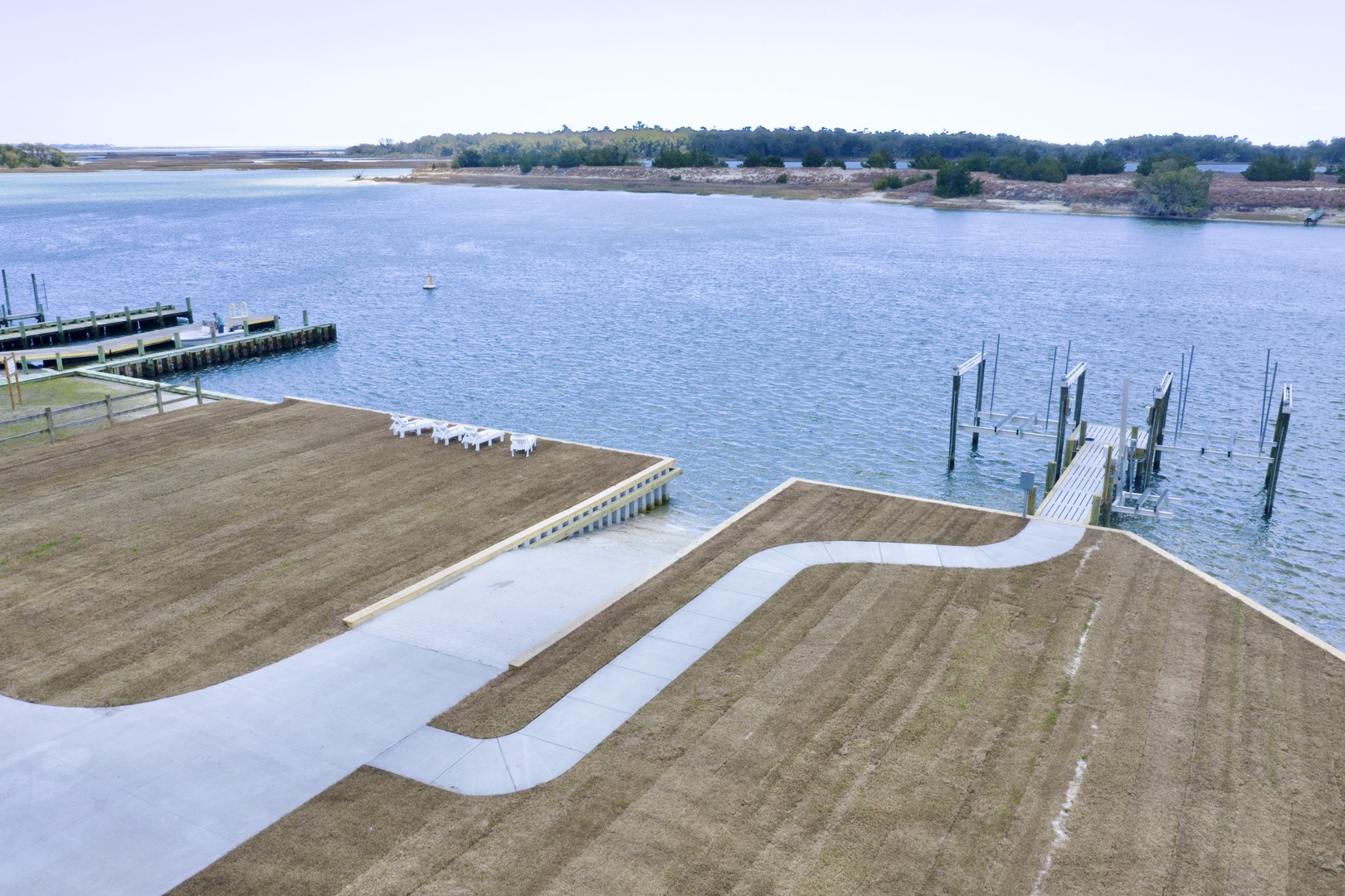 Waterfront property with private docks extending into calm bay waters, surrounded by natural coastline and distant wooded areas.