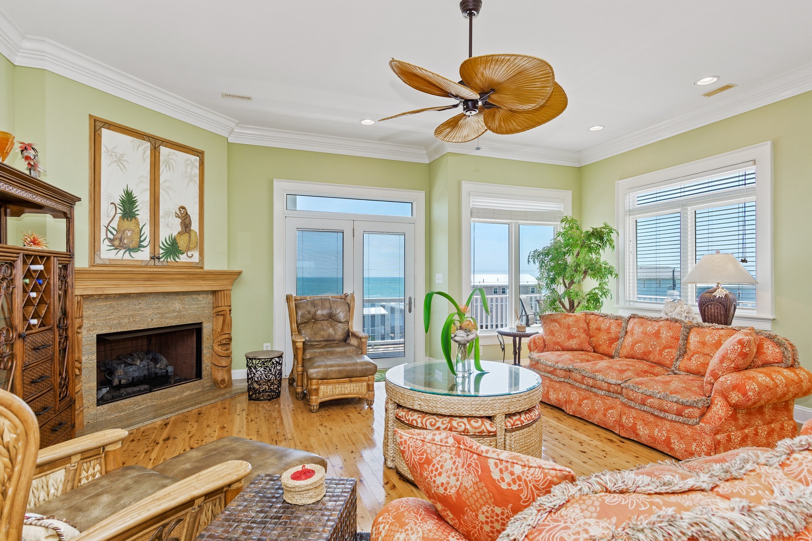 Relax in your tropical-themed living room where ocean breezes meet cozy comfort, complete with fireplace and stunning sea views.